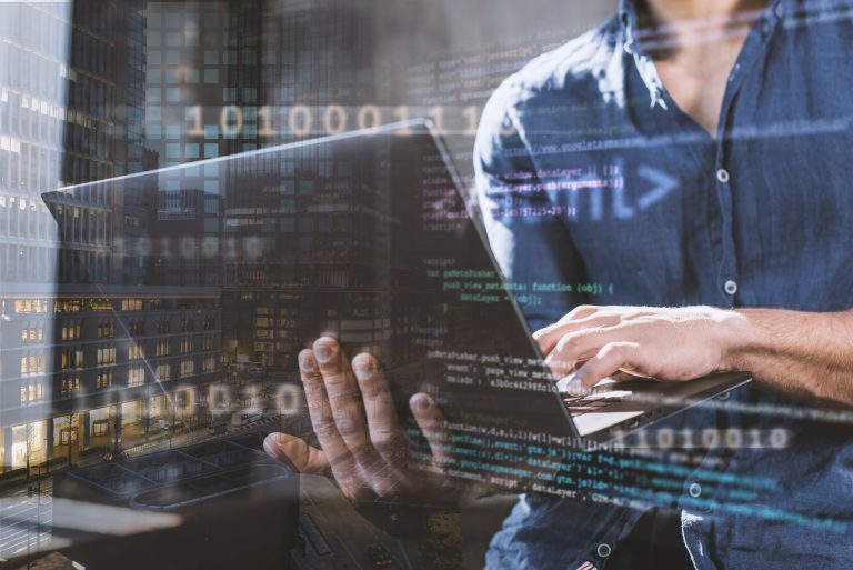 Técnico informático trabajando con un portátil sobre un fondo de código y datos